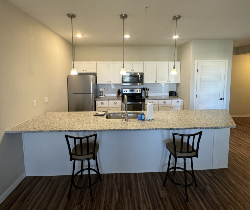 Dining and kitchen area in open-plan apartment with breakfast bar seating and modern finishes.